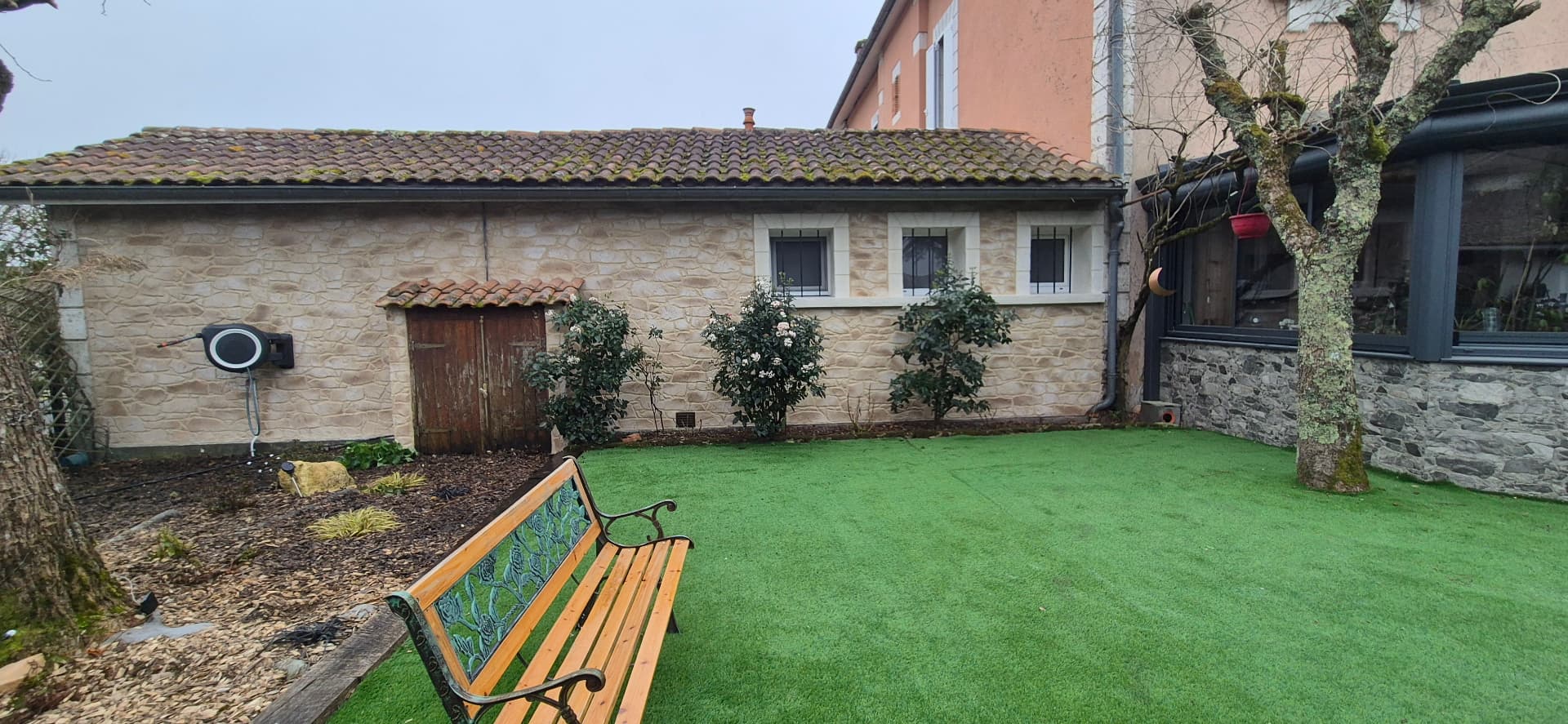 Jardin et façade habillée en imitation pierre claire, avec banc en bois et pelouse — PierreInnovRénov, Landes